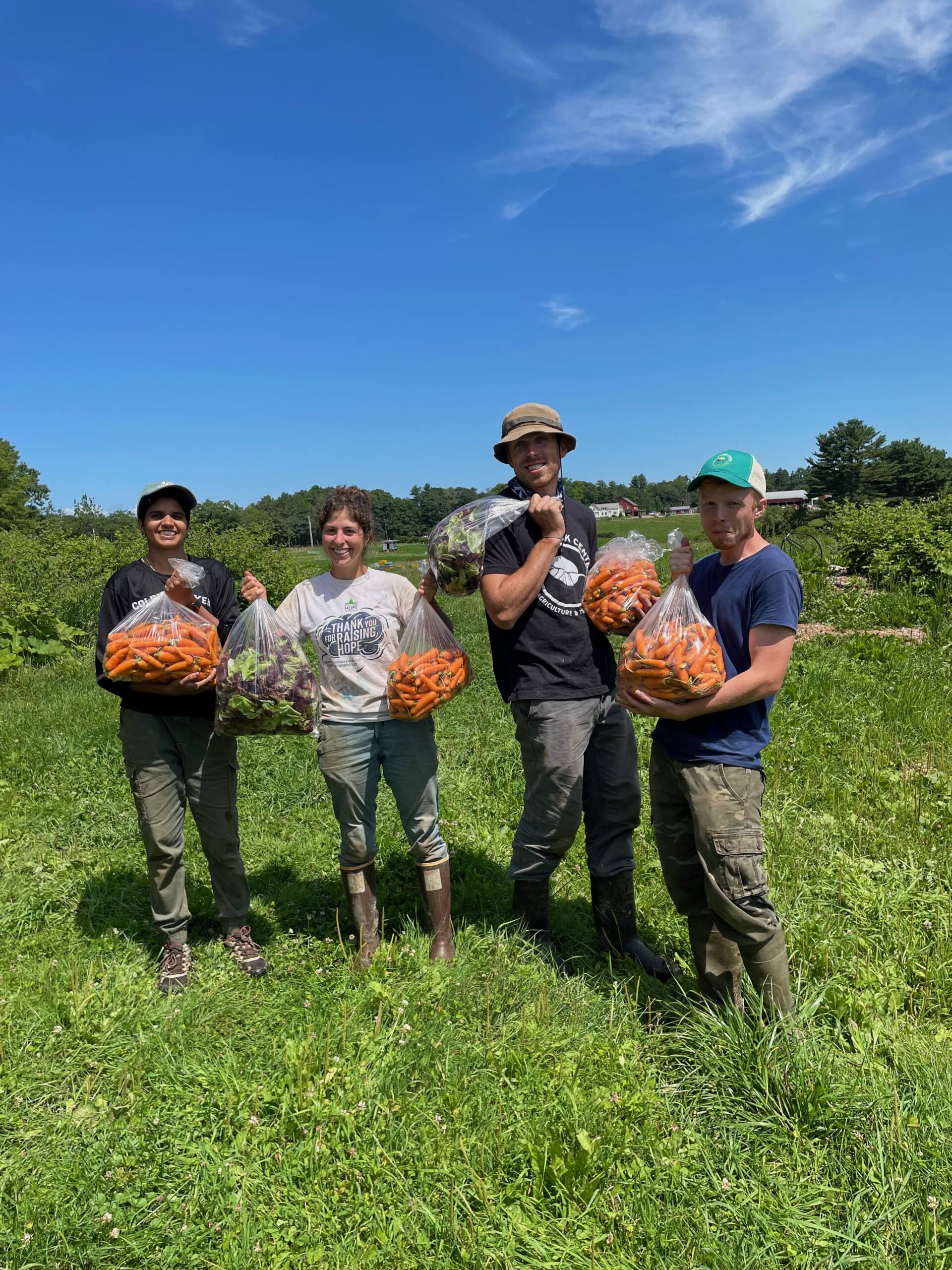 Farm staffers holding bags of vegetables